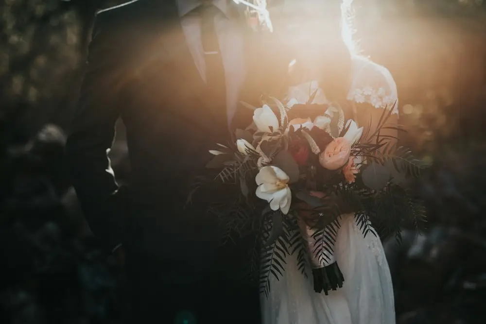A bride holding a bouquet of white roses in evening light